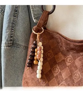 Detail of vintage beaded charm with totem patterns on a brown suede shoulder bag