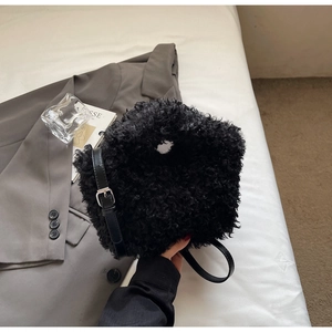 Close-up of black fuzzy plush shoulder bag with textured faux shearling and leather strap