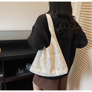 Detail of laser-cut floral patterns on a beige tote bag shown in a lifestyle setting