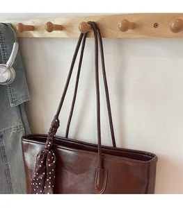 Detail of comfortable thin shoulder straps and silk scarf on dark brown tote bag