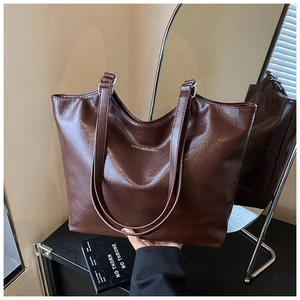 Detail of a large vintage dark brown tote bag in textured faux leather with white branding