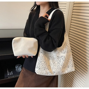 Detailed view of white laser-cut hollow tote bag with matching inner zipper pouch