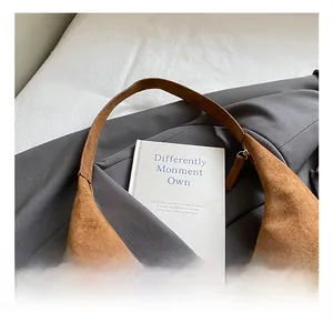 Details der Textur einer braunen Wildleder-Hobo-Tasche mit bequemem Griff und Metallreißverschluss