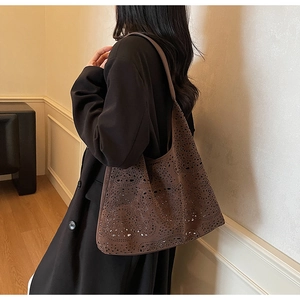 Close-up of laser-cut floral patterns on dark brown faux suede tote bag