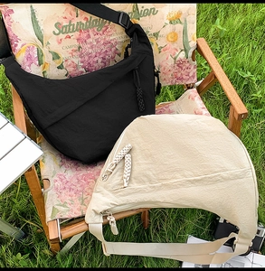 Outdoor setup of black and beige crescent crossbody bags with adjustable straps
