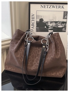 Detail of leopard print tote bag with black leather strap and silver metal chain link