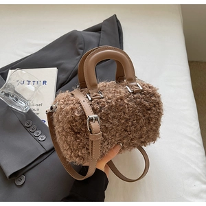 Detailed view of brown faux shearling cylindrical bag with leather handle and silver hardware