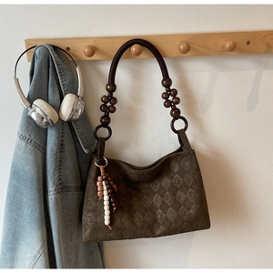 Detail of quilted coffee suede shoulder bag with retro wooden beads and woven strap