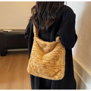 Close-up of fluffy faux fur tote bag with brown tiger stripes worn on model's shoulder