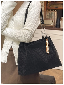 Detail of black leopard print tote bag with silver chain strap and wooden bead charm