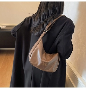 Detail of the brown textured leather hobo bag with an embossed fashion label on the front