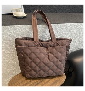 Close-up of brown quilted nylon tote bag with diamond pattern on a wooden table