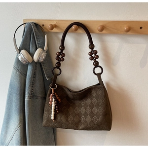 Detailed view of quilted dark brown suede bag featuring unique beaded handle and fringe