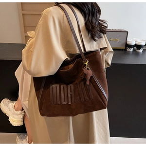 Detail of MOACHI logo embossing on brown large capacity tote bag with elephant charm