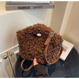 Detail of plush brown teddy fabric texture and adjustable leather strap on handbag