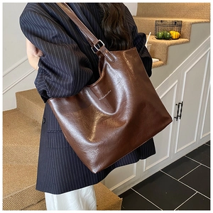 Brown oil wax leather tote bag with brand logo shown in a lifestyle street setting