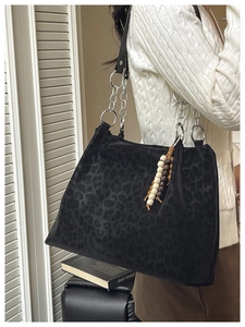 Close-up of leopard print tote bag featuring silver chain strap and beaded keychain