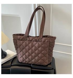 Detail of dark brown quilted nylon tote bag placed on a modern bench in a cozy setting