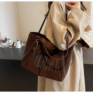 Detail of dark brown suede tote bag with MORAI embroidery and leaf leather charm