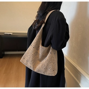 Detail of beige laser-cut floral pattern on a large tote bag with a soft faux suede texture