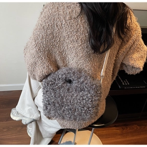 Detail of grey fuzzy faux lamb wool shoulder bag texture with slim white leather strap