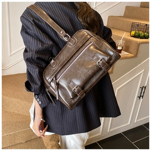 Detail of dark brown vintage pillow bag with metal buckle front pockets and shoulder strap
