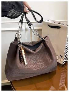 Detailed shot of dark brown leopard embossed tote bag with silver chain strap and beaded tassel