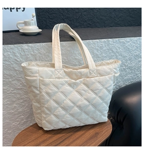Detail of white quilted nylon tote bag with rhombus pattern and wide shoulder straps