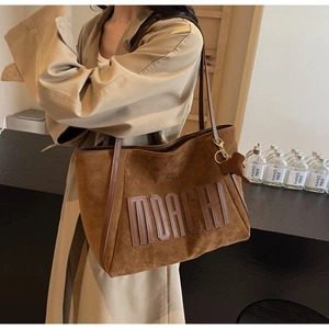 Macro shot of MOACHI logo on brown suede tote bag with animal charm detail