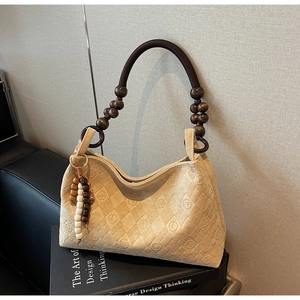 Detail of beige monogram bag featuring unique wooden bead handle and rustic cord straps