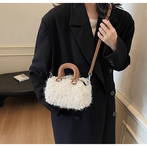 Detail of white fluffy crossbody bag with dark brown leather handle and silver hardware