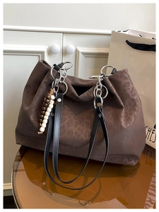 Detail of dark brown leopard pattern tote bag with silver chain and beaded charm