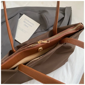 Detail of dark brown nylon tote bag with leather straps and secure zipper closure