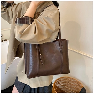 Detail of dark brown tote bag with premium lychee grain texture and side stitching