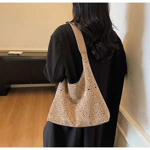 Detail view of beige hollow-out tote bag showing intricate laser-cut patterns on the shoulder