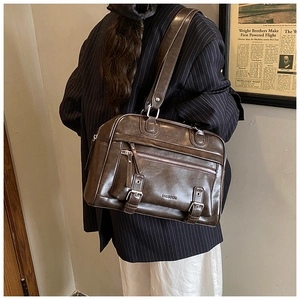 Detailed macro view of dark brown retro PU leather tote with zipper pockets and buckle