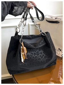 Detail of leopard print tote bag featuring silver chain handle and beaded charm
