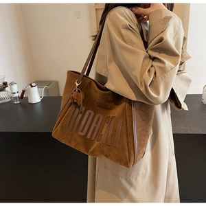 Detail of dark brown suede tote bag with embossed logo and cute elephant charm