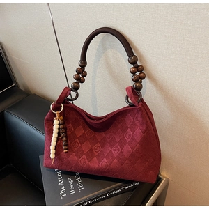 Detail of burgundy suede tote with quilted patterns and artisan wooden bead handle