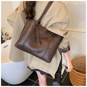 Vue latérale d'un grand sac cabas marron café porté par un mannequin dans une pièce
