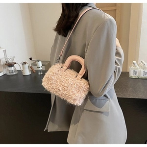 Close-up of pink faux shearling handbag with leather handles worn by a model