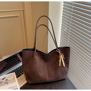 Detail of dark brown suede tote bag with wood bead charm and minimalist texture