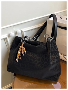 Detail of black leopard print tote bag with silver rings and wood bead charm decoration