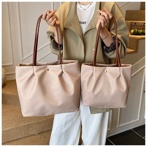 Detail view of pink tote bag set with brown handles and gold button held by model