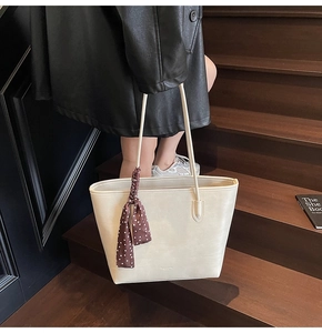 Detail of off-white leather tote bag with a polka dot silk scarf wrapped on the handle