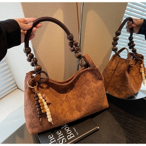 Detail of vintage brown suede tote with diamond quilting and decorative wooden bead handles