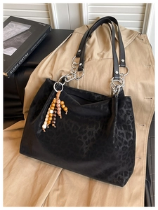 Detail view of leopard print tote bag with silver chain handles and wooden bead charm
