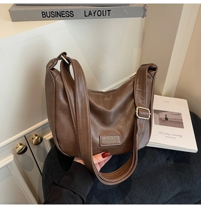 Detail of a brown pebbled leather hobo bag with a wide strap and silver metal buckle