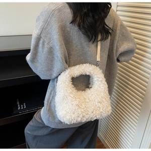 Detail of white plush shoulder bag featuring soft faux fur texture and detachable strap