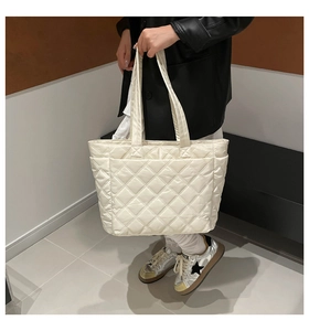 White quilted nylon tote bag with rhombus pattern shown on model in a minimalist setting